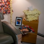 217: Donation Room Detail - Mixed media sculpture, installation Insulation foam, found photographs, tissue, medical recliner by Suzie Marco